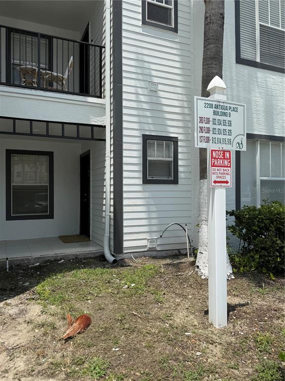 The exterior of a multi-story apartment building features a parking sign and a ground-floor patio — 2208 ANTIGUA PLACE UNIT 914, KISSIMMEE, FL