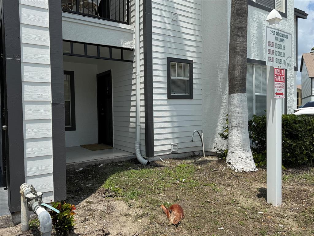 The exterior of a multi-story apartment building features white siding, a covered entryway, and signage — 2208 ANTIGUA PLACE UNIT 914, KISSIMMEE, FL