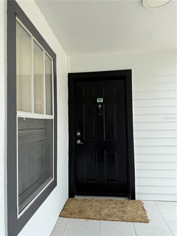 A black front door with a window to the left on a tiled porch — 2208 ANTIGUA PLACE UNIT 914, KISSIMMEE, FL