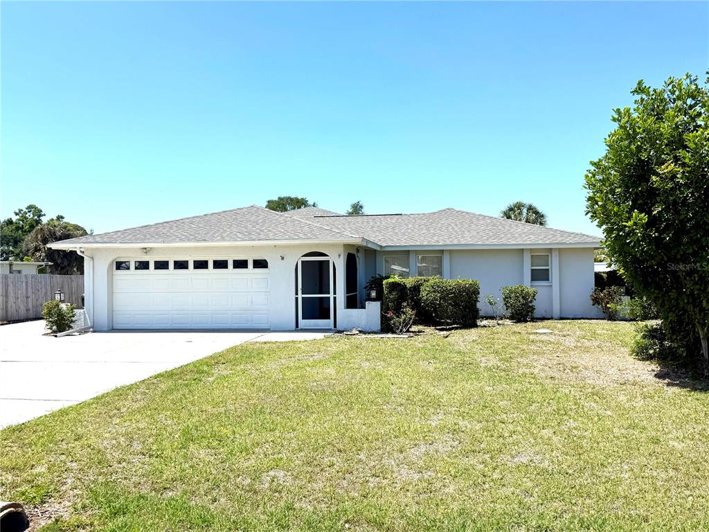 A single-story house with a white exterior, a two-car garage, and a front lawn — 1505 MORGAN STREET, NOKOMIS, FL