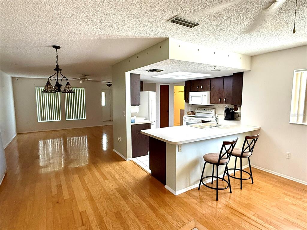 An open-concept kitchen with dark cabinets and a breakfast bar overlooks a dining area — 1505 MORGAN STREET, NOKOMIS, FL