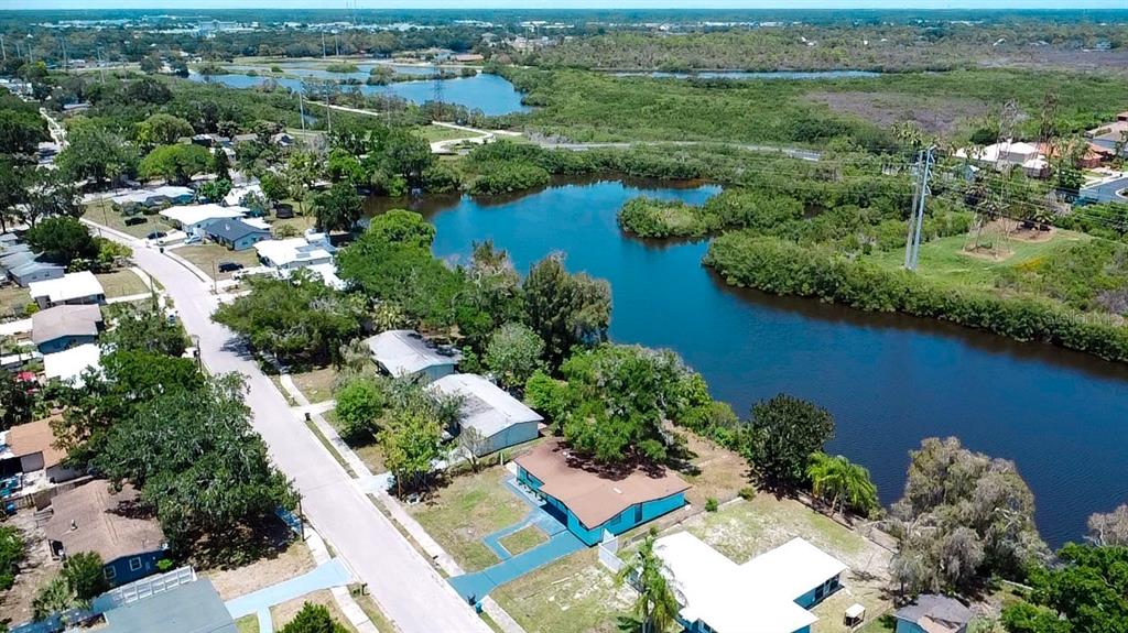 An aerial view shows a residential street with houses situated along a large, winding lake — 415 COUNTRY CLUB DRIVE, OLDSMAR, FL