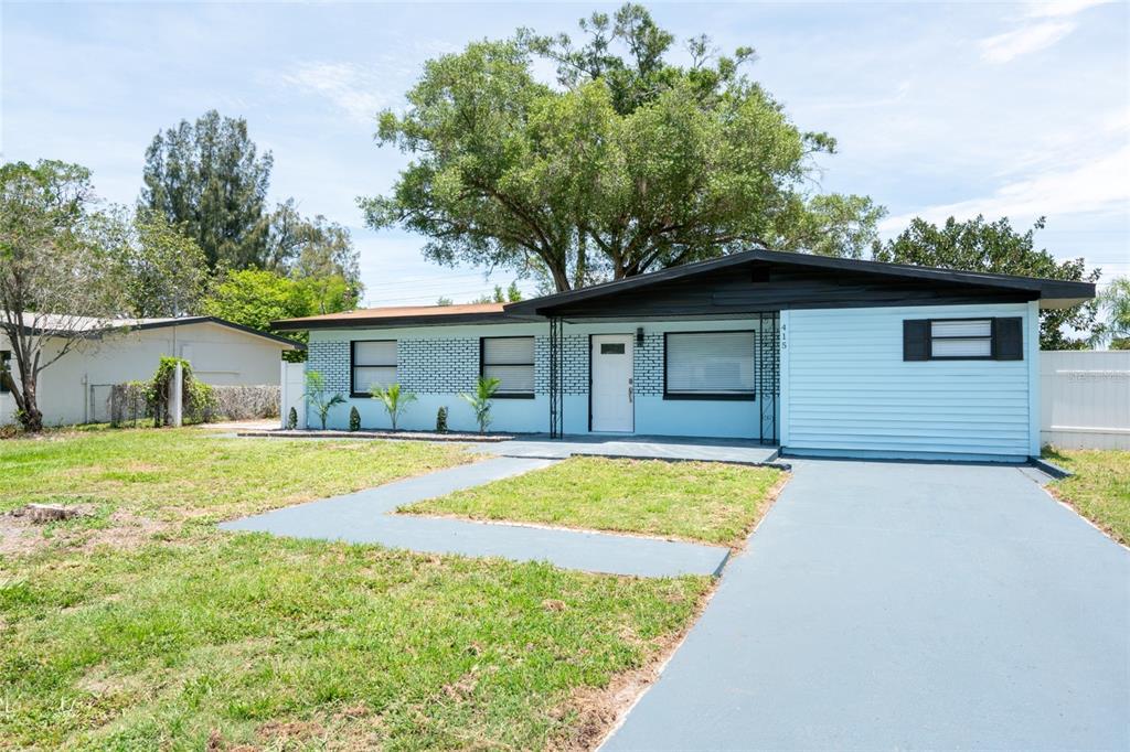 A light blue single-story house with a black roof and a concrete driveway — 415 COUNTRY CLUB DRIVE, OLDSMAR, FL