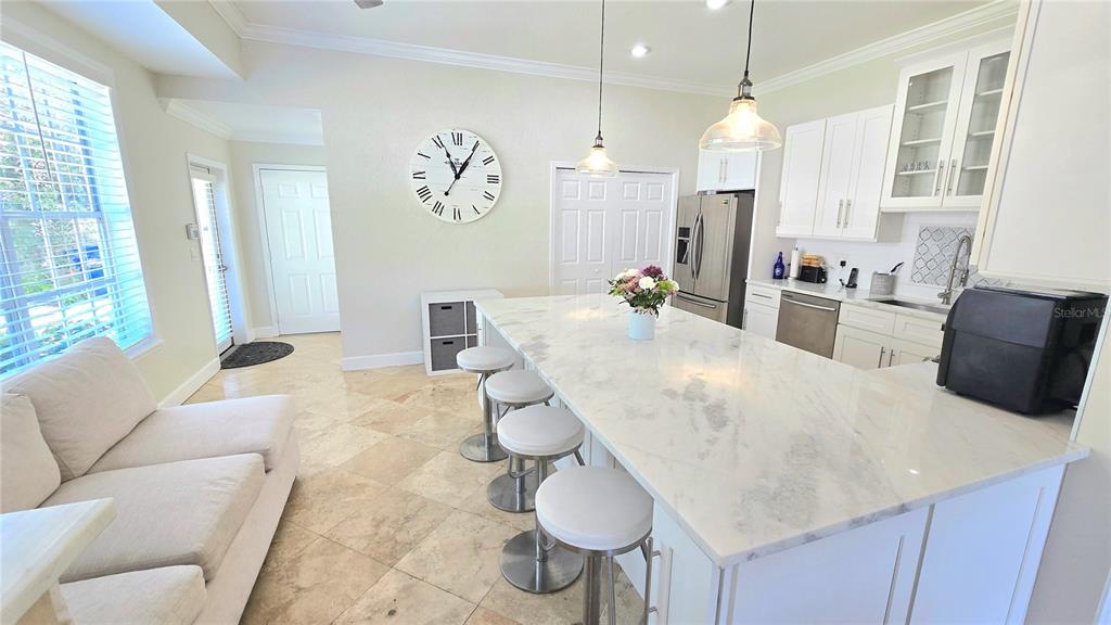 A kitchen with a large marble island, white cabinetry, and an adjacent living area — 1806 LAGO VISTA BOULEVARD, PALM HARBOR, FL