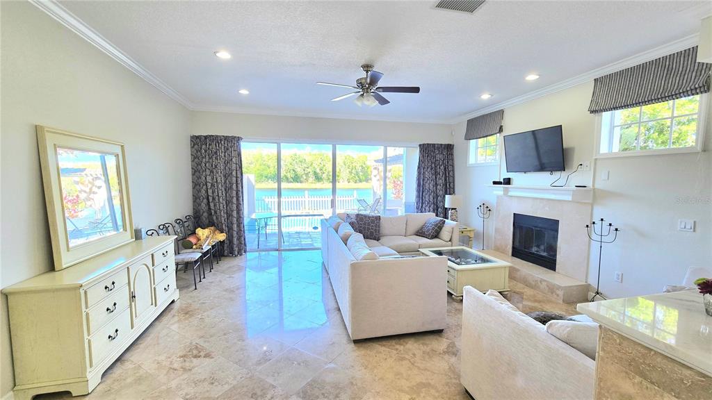 A living room with tile floors, a fireplace, a sectional sofa, and sliding glass doors — 1806 LAGO VISTA BOULEVARD, PALM HARBOR, FL