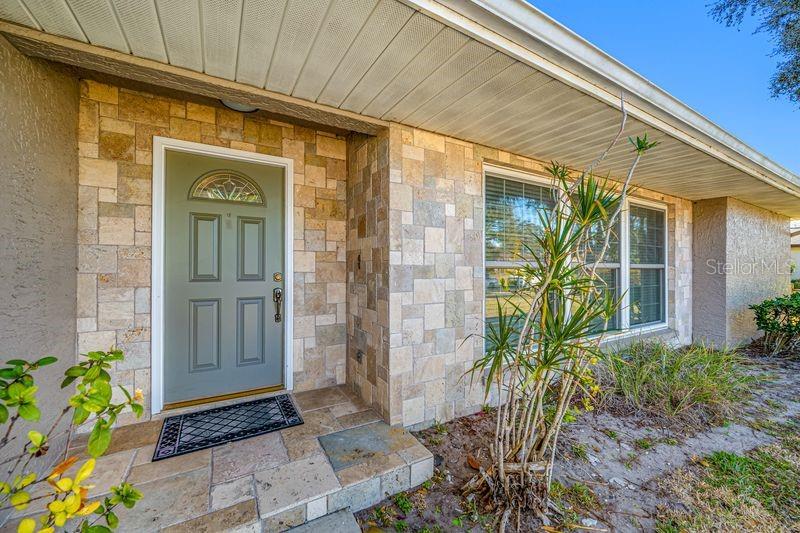 A front entrance features a sage green door, stone facade, and a small porch — 3241 BUCKHORN DR, CLEARWATER, FL