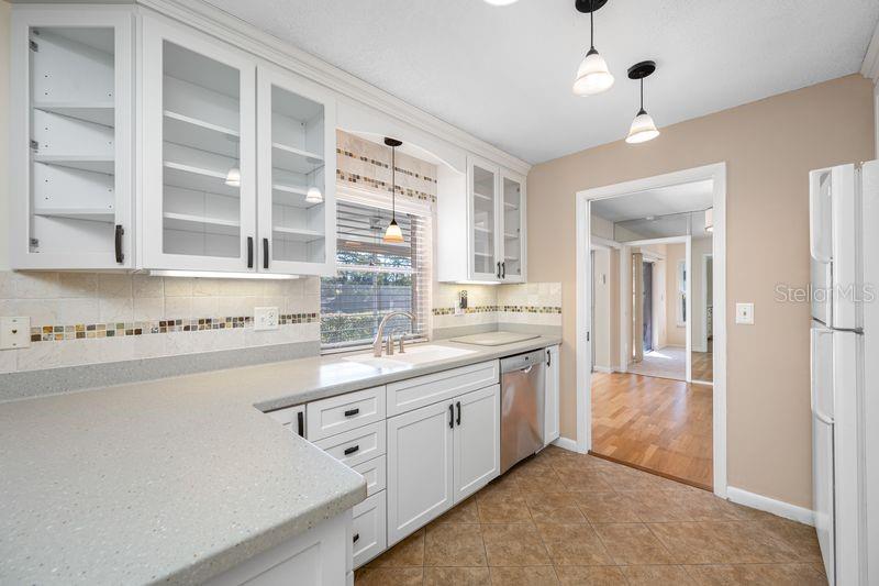 A kitchen with white cabinets, light countertops, a stainless steel dishwasher, and tile flooring — 3241 BUCKHORN DR, CLEARWATER, FL