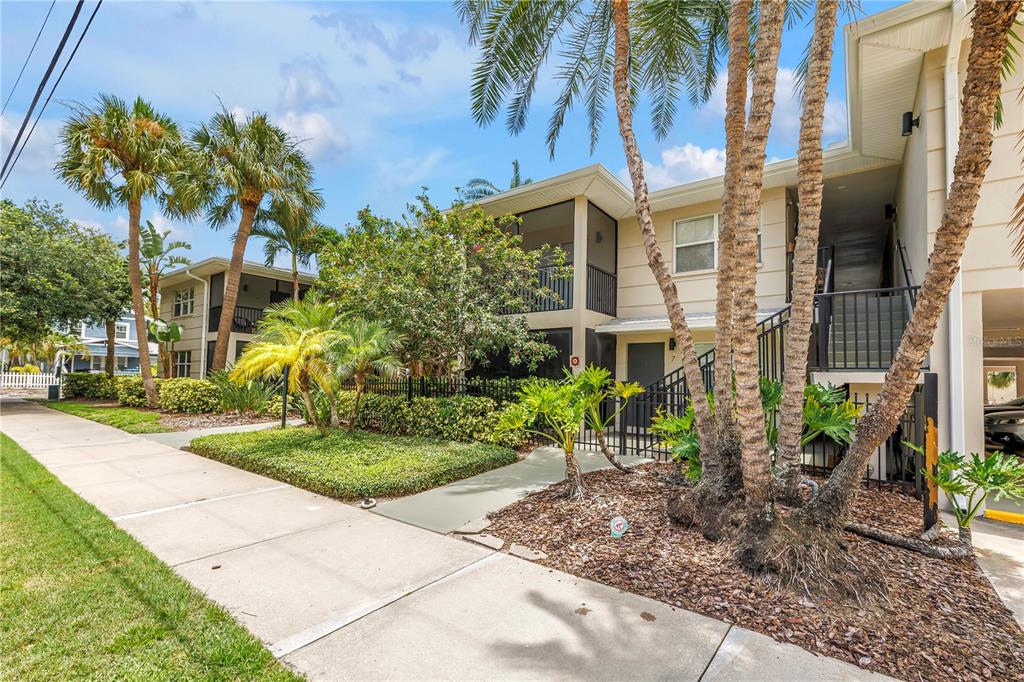 A two-story apartment building exterior with a screened balcony, palm trees, and a sidewalk — 555 3RD STREET N UNIT 13, ST PETERSBURG, FL