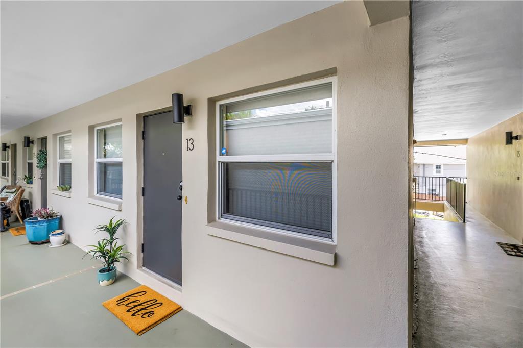 The exterior view shows the entrance to unit 13 with a gray door and window — 555 3RD STREET N UNIT 13, ST PETERSBURG, FL