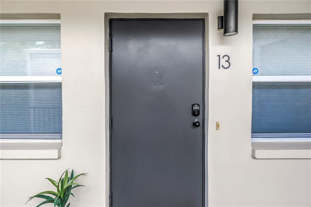 A dark gray front door with a digital lock is centered between two windows — 555 3RD STREET N UNIT 13, ST PETERSBURG, FL