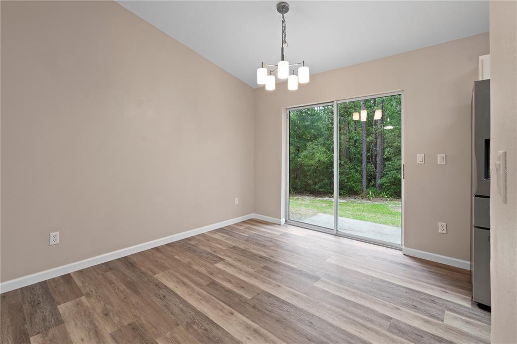 An open-concept living area features wood-look flooring, a ceiling fan, and a kitchen pass-through window — 8392 SW 139TH LANE ROAD, OCALA, FL
