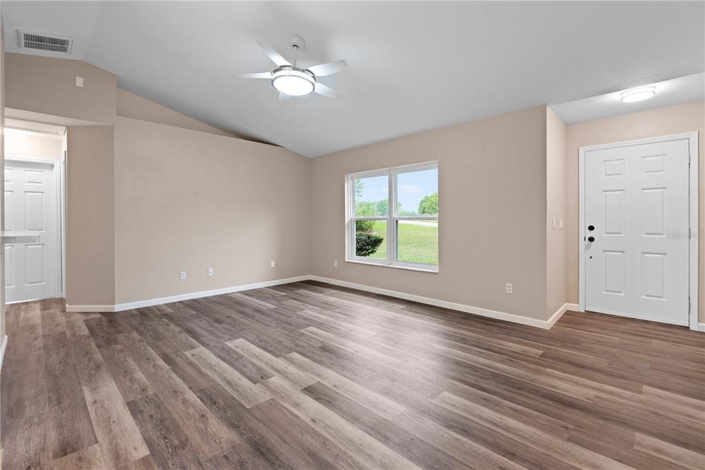 An empty dining room with wood-look flooring, a modern chandelier, and a sliding glass door — 8392 SW 139TH LANE ROAD, OCALA, FL