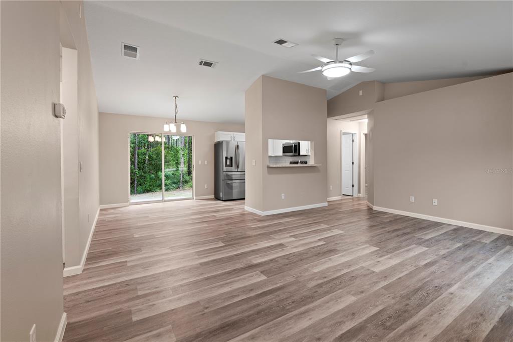 A kitchen features white cabinets, stainless steel appliances, a subway tile backsplash, and wood-look flooring — 8392 SW 139TH LANE ROAD, OCALA, FL