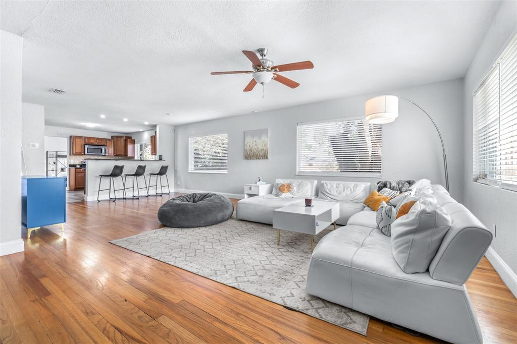 A living room with a white sectional sofa, beanbag chair, and an open kitchen beyond — 4116 N MARGUERITE STREET, TAMPA, FL