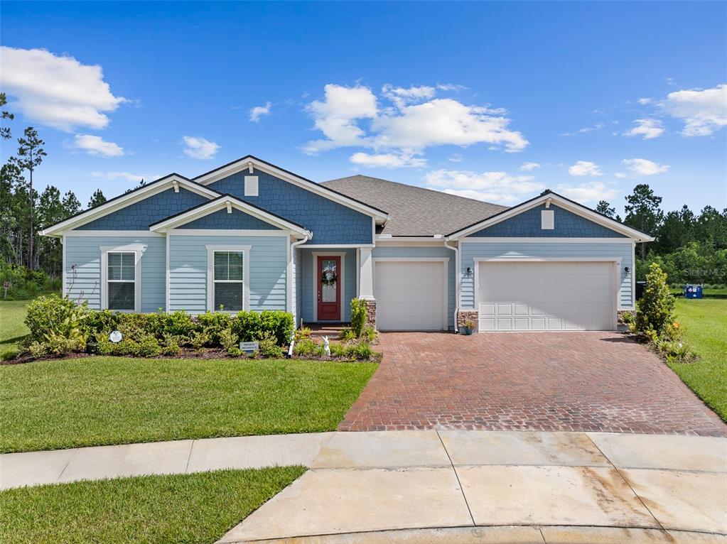 A single-story house with blue siding, a brick driveway, and a two-car garage — 83 REVERIE DRIVE N, PALM COAST, FL