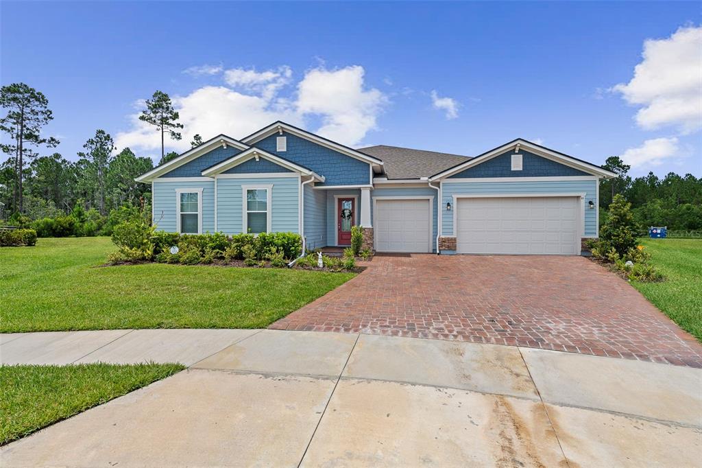 A blue, single-story house with a brick driveway and a two-car garage — 83 REVERIE DRIVE N, PALM COAST, FL