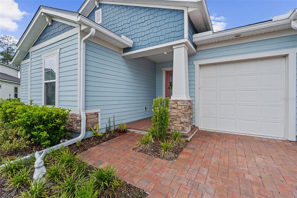 The exterior of a blue house features a brick walkway, a garage, and a covered entryway — 83 REVERIE DRIVE N, PALM COAST, FL