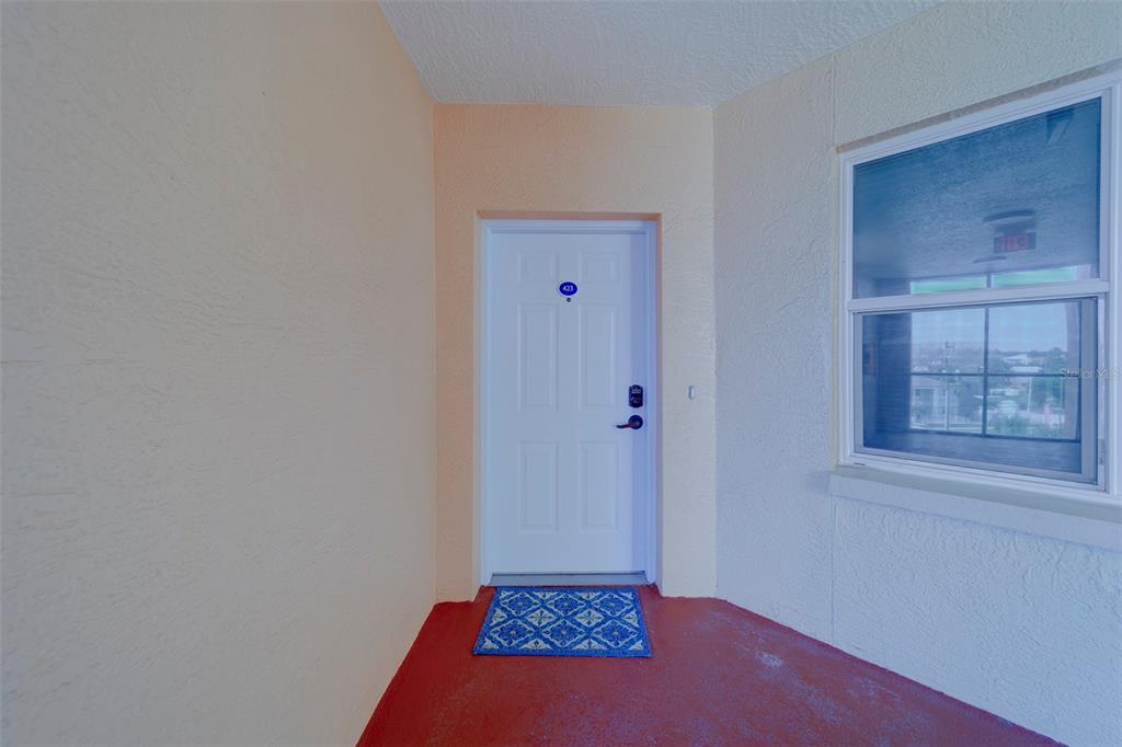 A white entry door with a blue mat sits on a red porch — 16700 GULF BOULEVARD UNIT 423, NORTH REDINGTON BEACH, FL