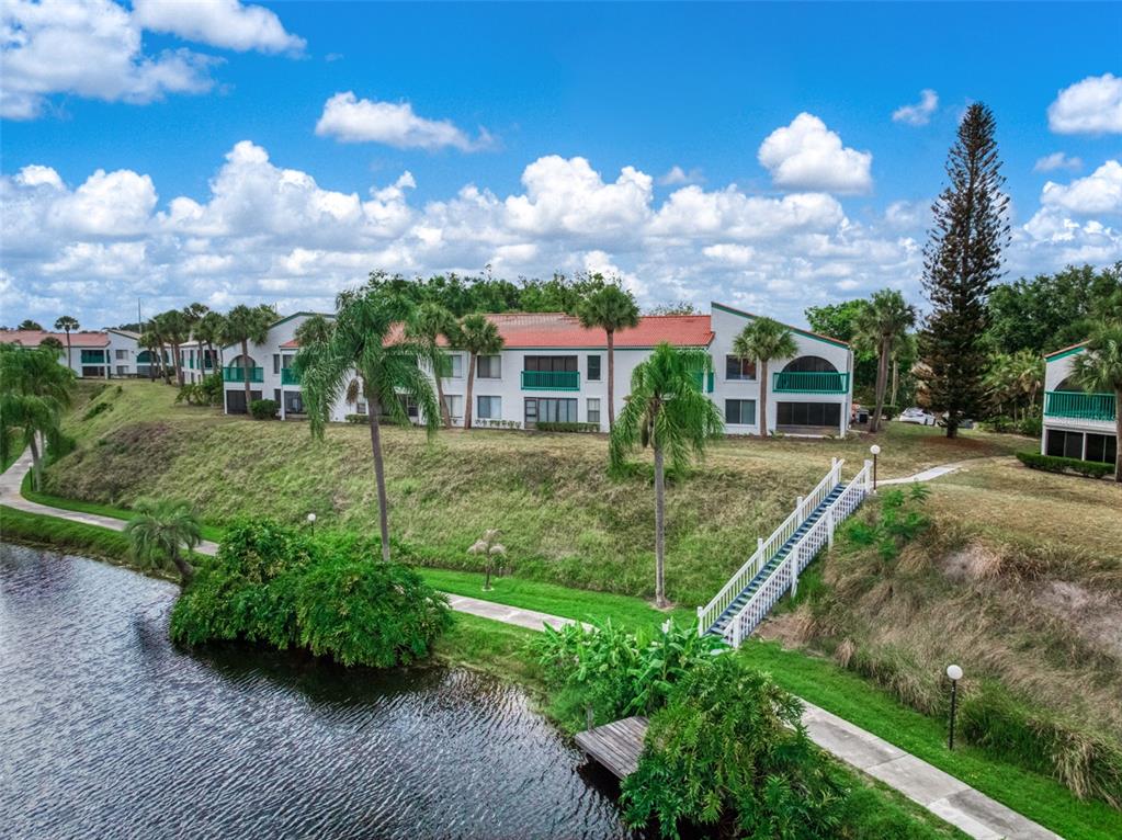 A multi-story apartment building sits on a grassy hill overlooking a small lake — 4729 CASABLANCA CIRCLE UNIT C22, SEBRING, FL