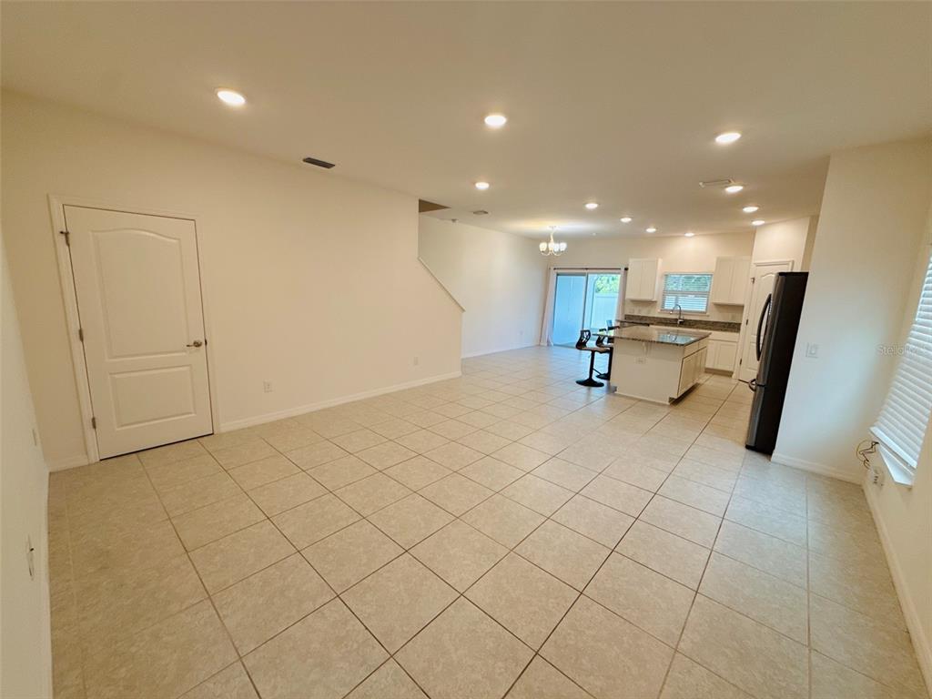 An open-concept kitchen and living area features light tile flooring and white cabinetry — 12547 NW 7TH PLACE, NEWBERRY, FL