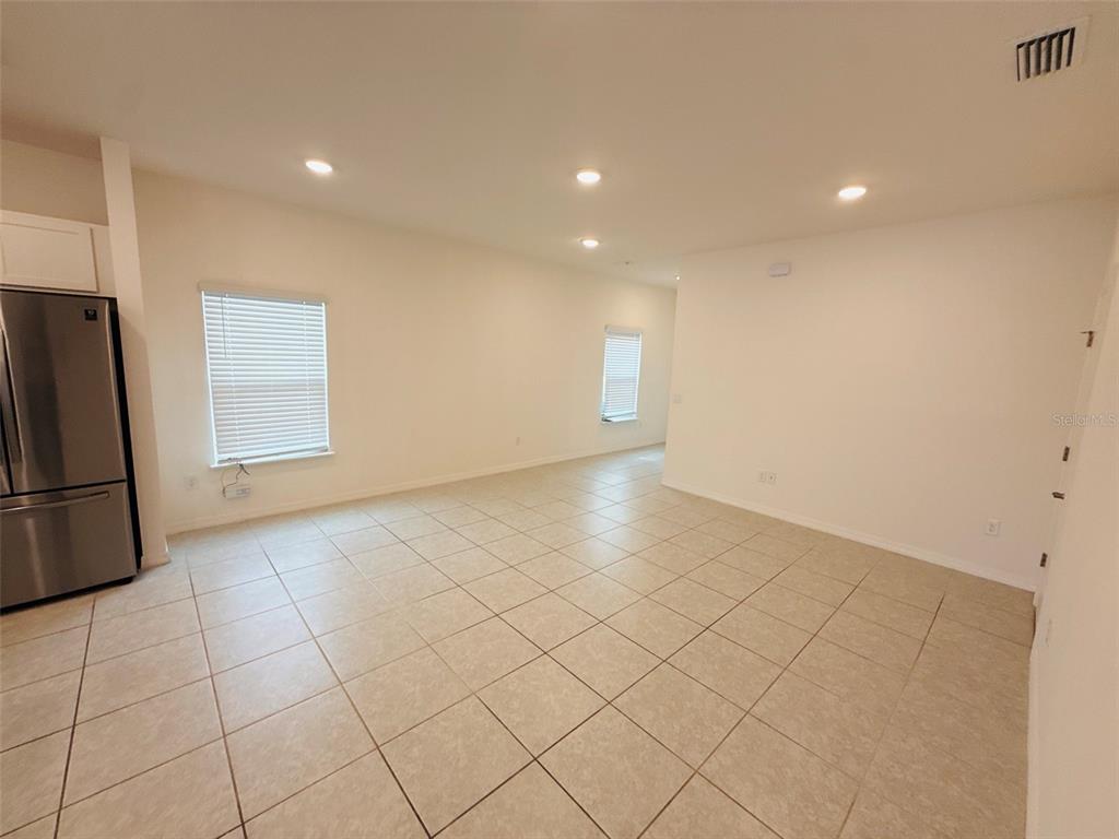 A bright, open-concept living area features light-colored tile flooring, recessed lighting, and white walls — 12547 NW 7TH PLACE, NEWBERRY, FL
