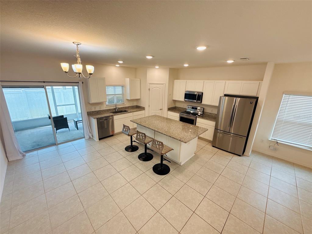 A kitchen features white cabinets, granite countertops, stainless steel appliances, and a central island — 12547 NW 7TH PLACE, NEWBERRY, FL