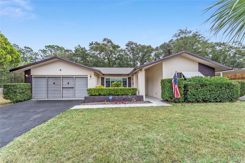 A single-story house with a two-car garage, beige siding, and a landscaped front yard — 8345 SW 200TH COURT, DUNNELLON, FL