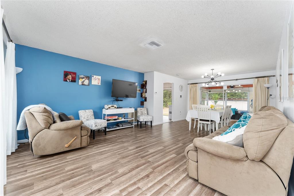 A living room with blue walls, wood-look flooring, and an adjacent dining area — 8345 SW 200TH COURT, DUNNELLON, FL