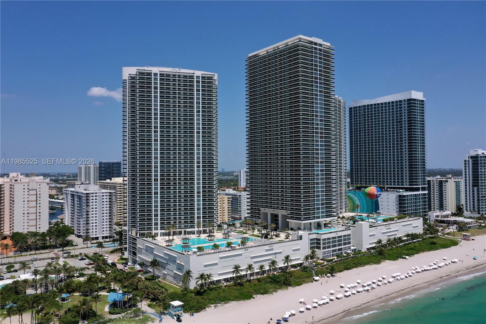An aerial view shows three tall residential towers situated along a sandy beach — 1800 S Ocean Drive # 3908, Hallandale Beach FL 33009, HALLANDALE BEACH, FL