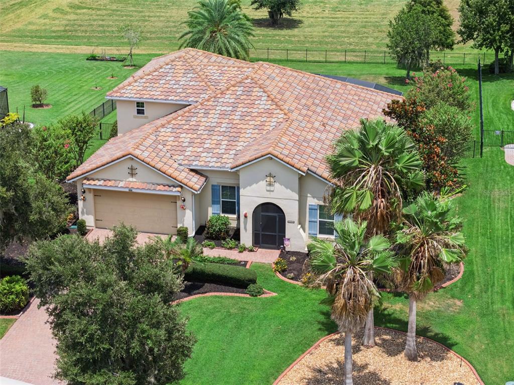 An aerial view of a tan house with a tiled roof, garage, and palm trees — 1511 GATEWAY LANE, KISSIMMEE, FL