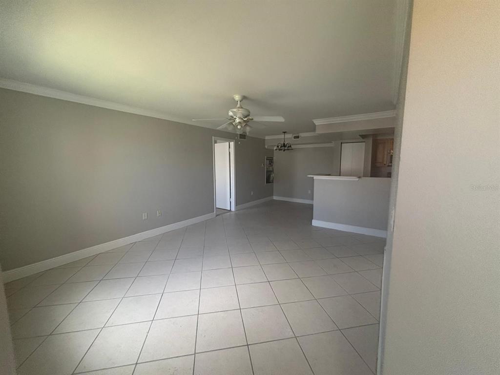 An open-concept living area features light gray walls, white crown molding, and diagonal tile flooring — 3038 PARKWAY BOULEVARD UNIT 208, KISSIMMEE, FL