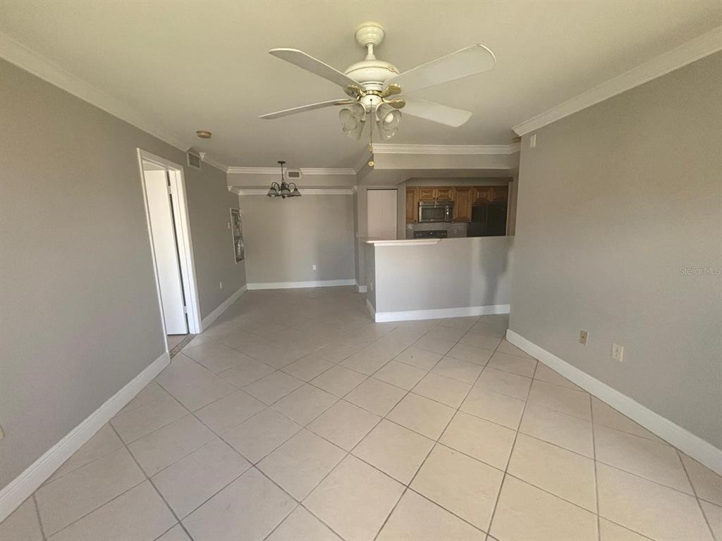 An open-concept living and dining area features tile flooring, a ceiling fan, and kitchen — 3038 PARKWAY BOULEVARD UNIT 208, KISSIMMEE, FL