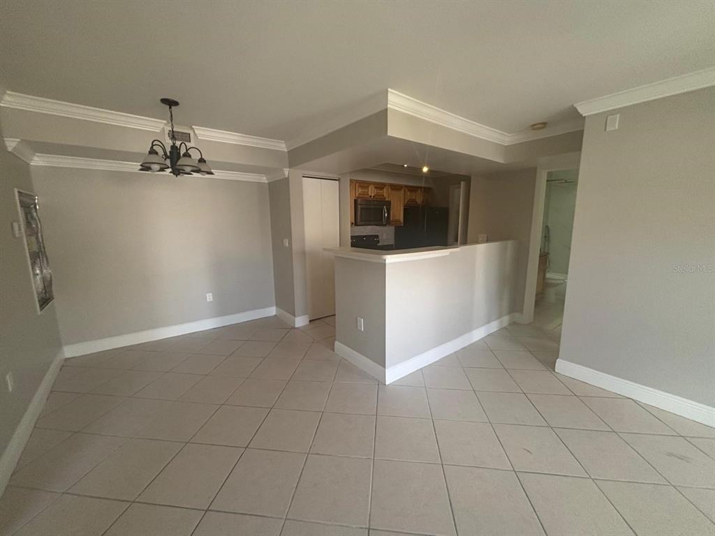 A dining area with a chandelier opens to a kitchen with a breakfast bar — 3038 PARKWAY BOULEVARD UNIT 208, KISSIMMEE, FL
