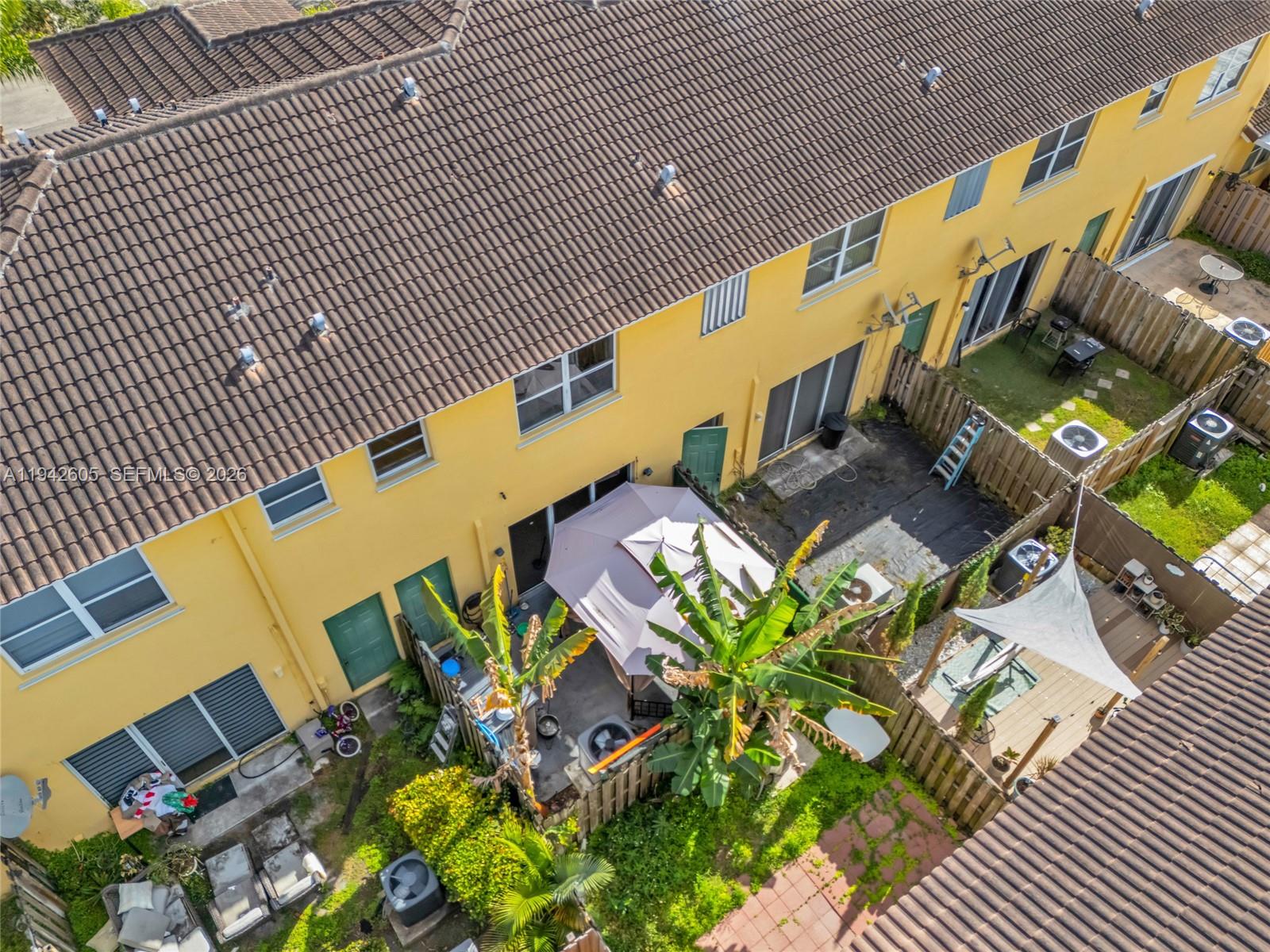 An aerial view shows the back of a yellow townhouse complex with fenced patios — 950 NE 42nd Pl, Homestead FL 33033, HOMESTEAD, FL