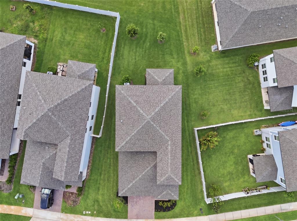 An aerial view shows three suburban houses with gray shingled roofs and surrounding green lawns — 2365 TREASURE HILL STREET, MINNEOLA, FL