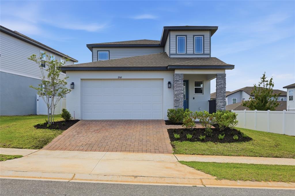 A two-story house with a white stucco facade, a stone-accented entryway, and a paved driveway — 2365 TREASURE HILL STREET, MINNEOLA, FL