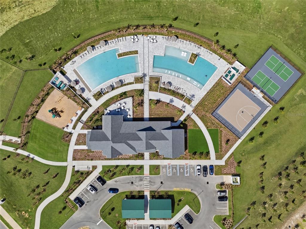 An aerial view shows a community clubhouse with two pools, a playground, and sports courts — 2365 TREASURE HILL STREET, MINNEOLA, FL