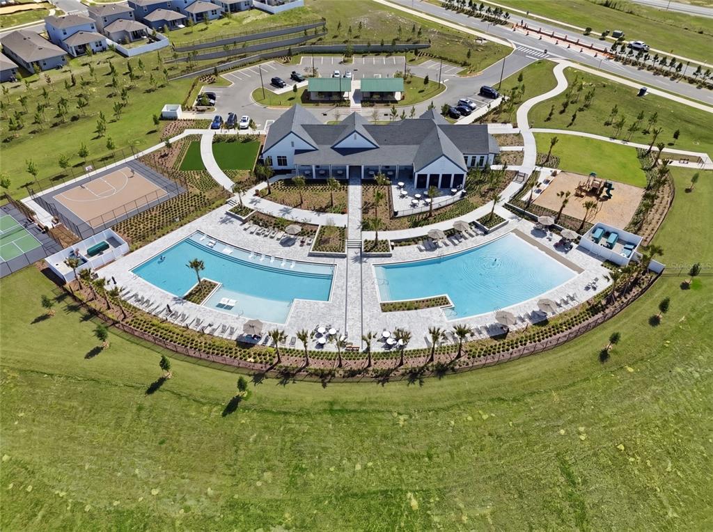 An aerial view shows a community clubhouse with two swimming pools, sports courts, and parking — 2365 TREASURE HILL STREET, MINNEOLA, FL