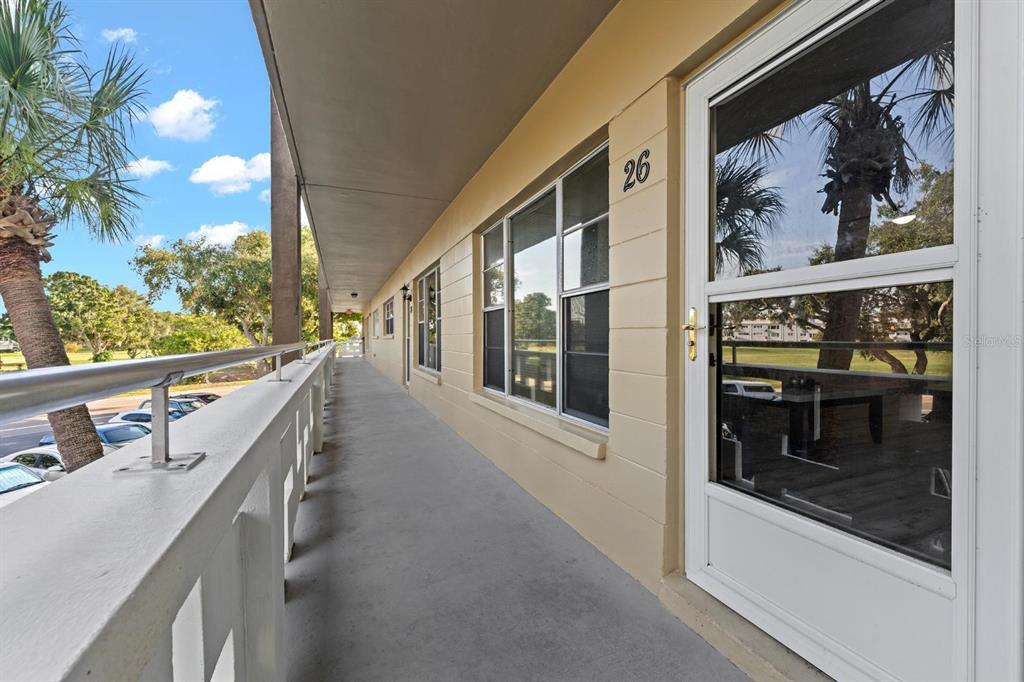 An exterior walkway with a metal railing overlooks a parking area and trees — 2416 WORLD PARKWAY BOULEVARD UNIT 26, CLEARWATER, FL