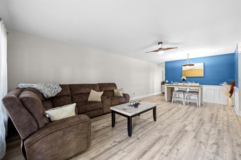 A living room with a brown sectional sofa, marble coffee table, and blue dining area — 2416 WORLD PARKWAY BOULEVARD UNIT 26, CLEARWATER, FL