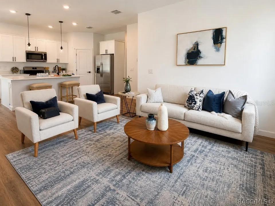 A living room with a sofa, two armchairs, a coffee table, and an open kitchen — 9509 N OLD MILL WAY, DUNNELLON, FL