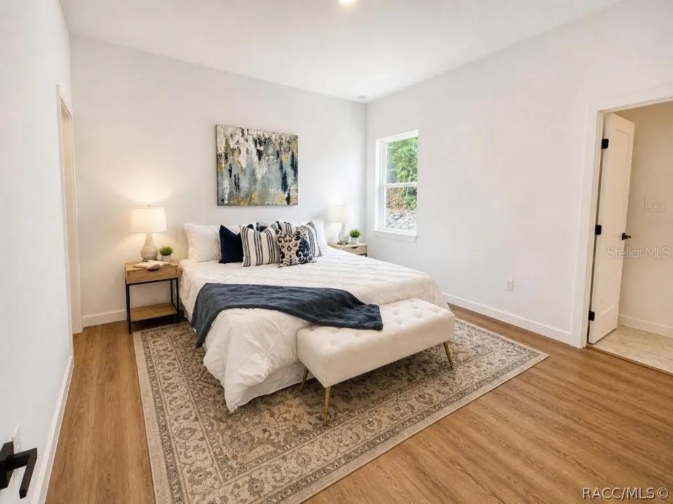 A bedroom features a bed with a white quilt, a patterned rug, and wood-look flooring — 9509 N OLD MILL WAY, DUNNELLON, FL