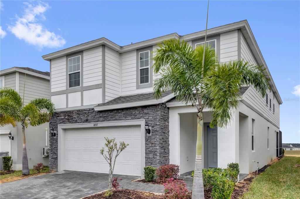 A two-story house with white siding, stone veneer, a two-car garage, and palm trees — 1897 SUMMER DRIVE, DAVENPORT, FL