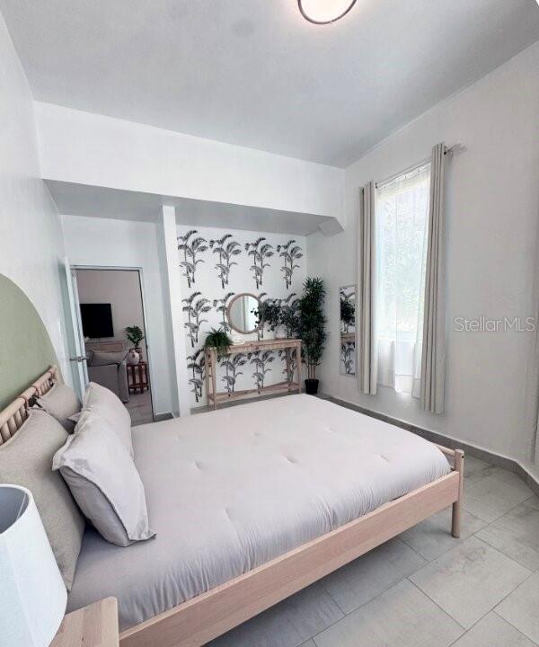 A bedroom features a light wood bed frame, palm-print wallpaper, and tile flooring — 250 CALLE DEL PARQUE UNIT 1A, SAN JUAN, PR