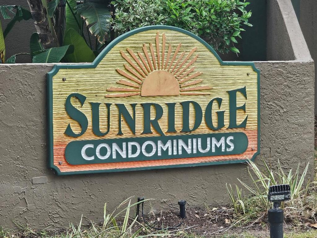 A sign for Sunridge Condominiums is mounted on a textured concrete wall with landscaping — 956 SUNRIDGE DRIVE UNIT H2, SARASOTA, FL