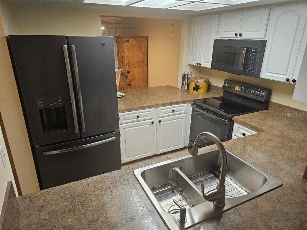 A kitchen with white cabinets, dark appliances, and brown countertops features a double-basin sink — 956 SUNRIDGE DRIVE UNIT H2, SARASOTA, FL