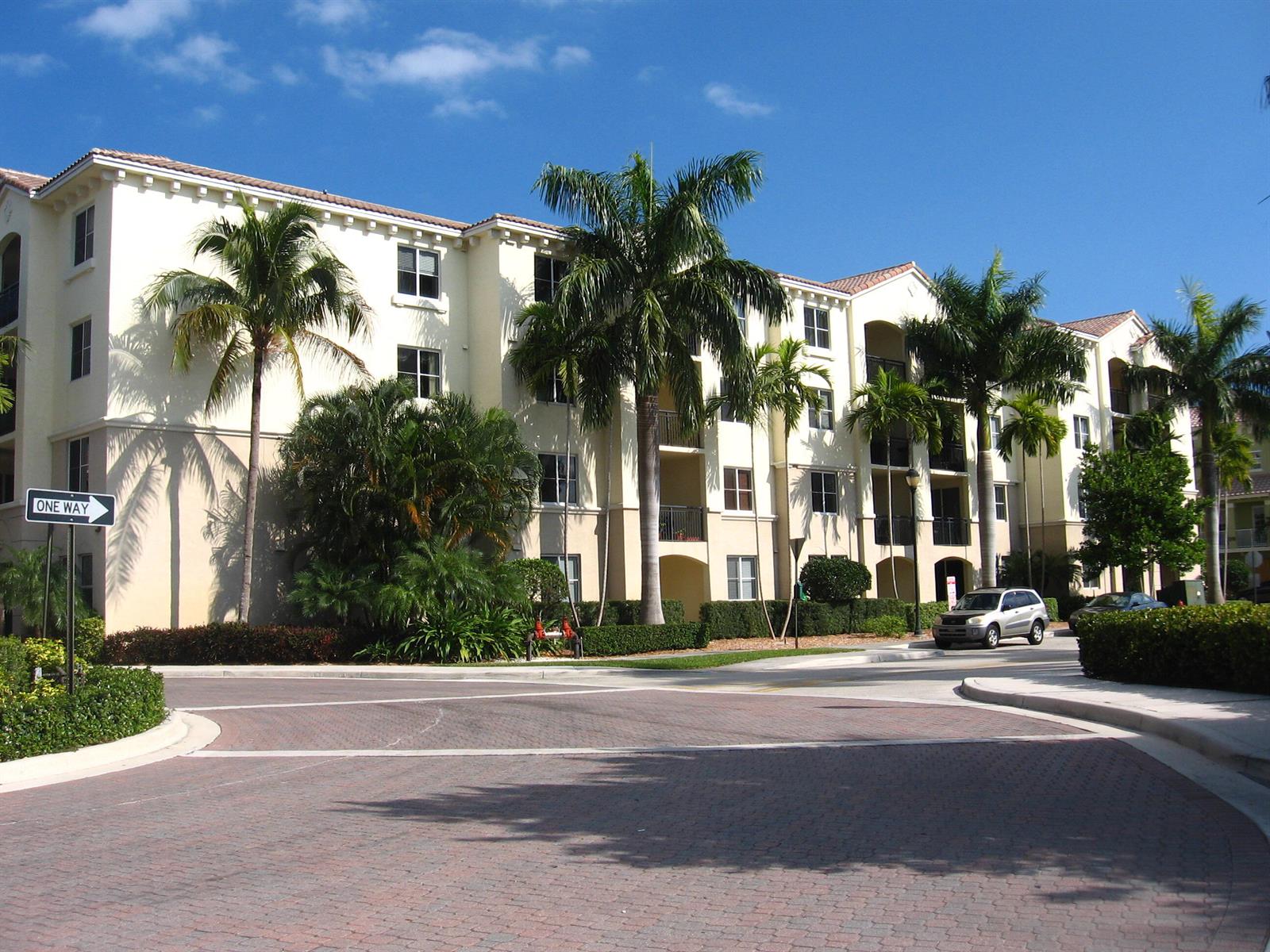 A multi-story apartment building with palm trees and a brick driveway under a blue sky — 3308 Renaissance Way, Boynton Beach FL 33426, BOYNTON BEACH, FL