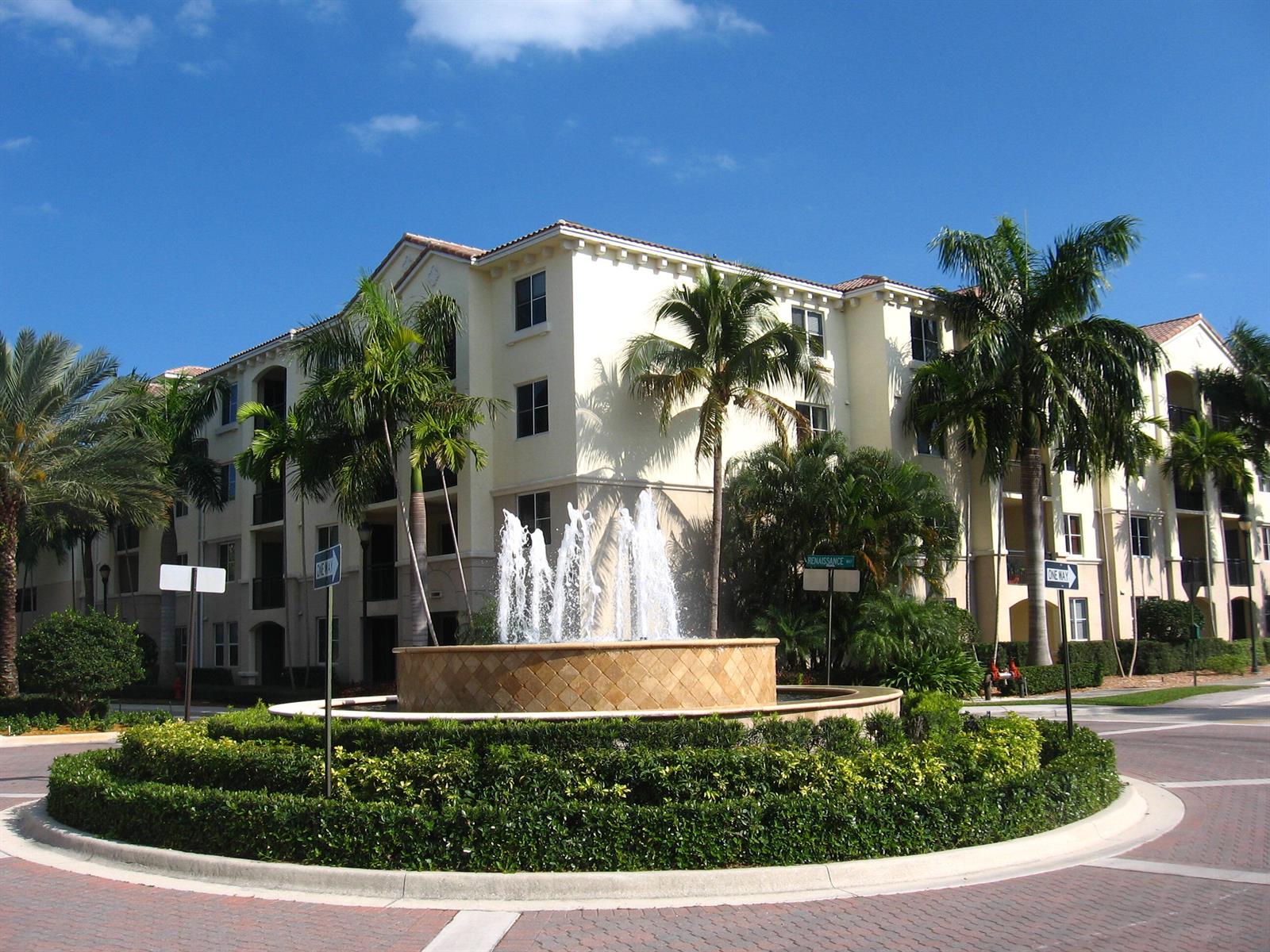 A multi-story apartment building stands behind a circular fountain surrounded by manicured hedges — 3308 Renaissance Way, Boynton Beach FL 33426, BOYNTON BEACH, FL