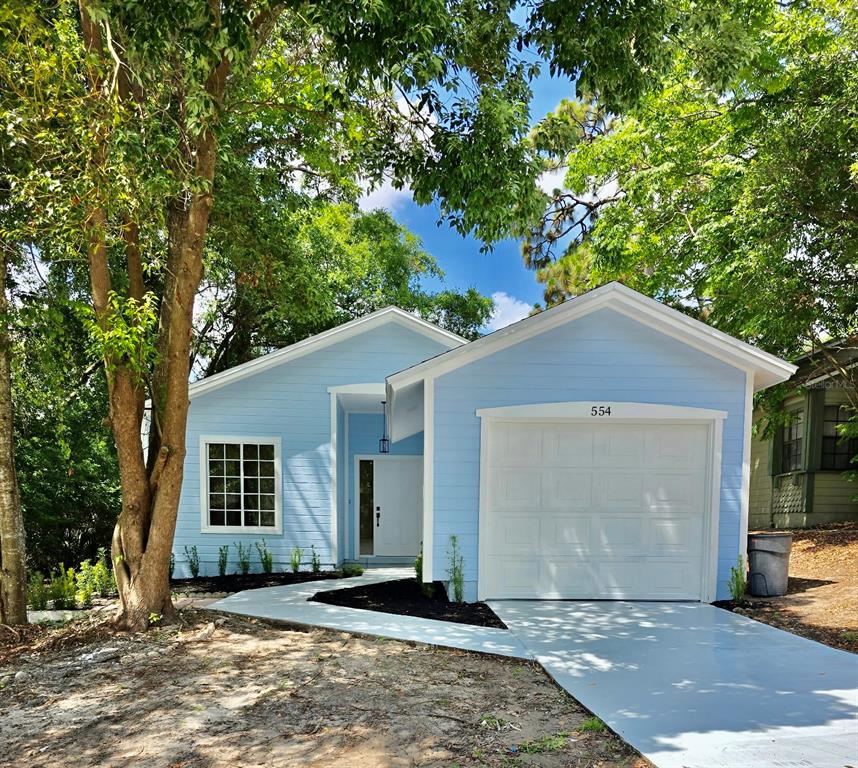 A light blue single-story house features a white garage door and a front entryway — 554 PORTLAND CIRCLE, APOPKA, FL