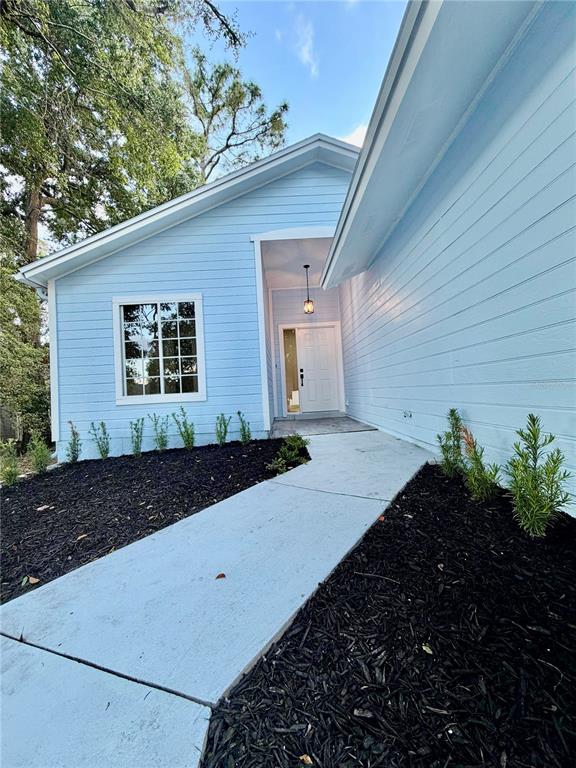 A light blue house exterior features a white front door and a concrete walkway — 554 PORTLAND CIRCLE, APOPKA, FL